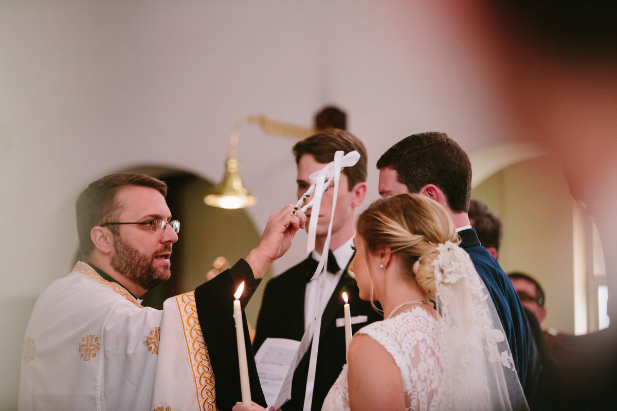 greek orthodox wedding ceremony preist putting crown on bride and groom