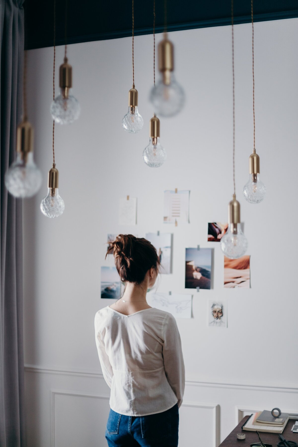 woman-under-pendant-lights-looking-at-the-photo-on-the-wall-3584992