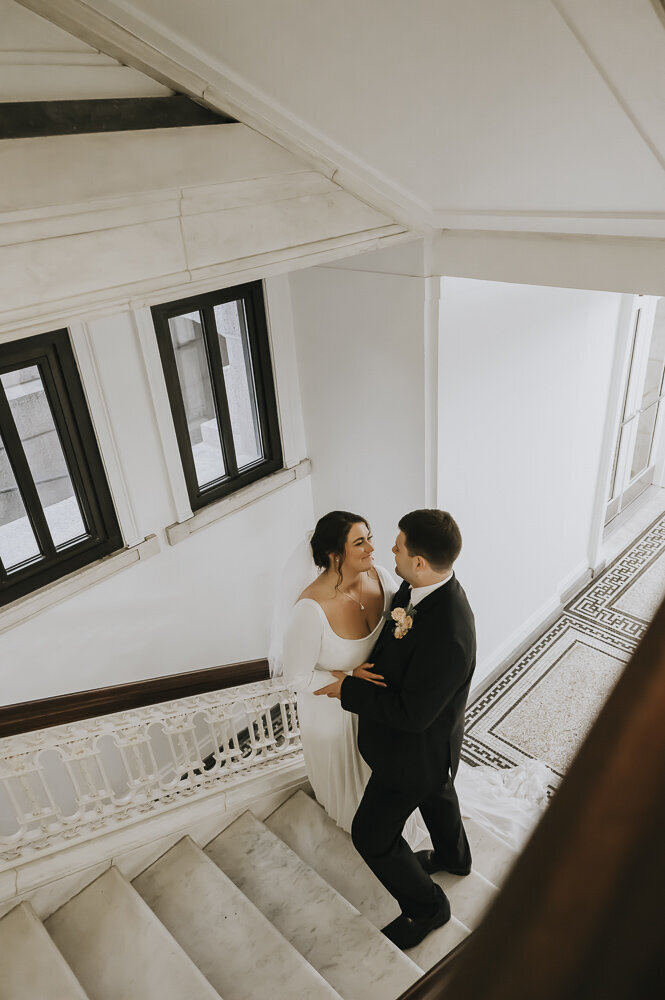 bride and groom smiling at each other on a stairwell