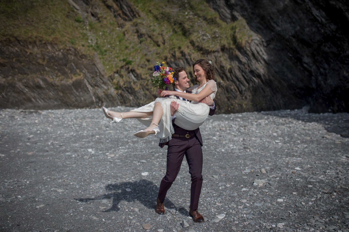 Groom carrying his Bride on the beach at Tunnels Beaches Wedding
