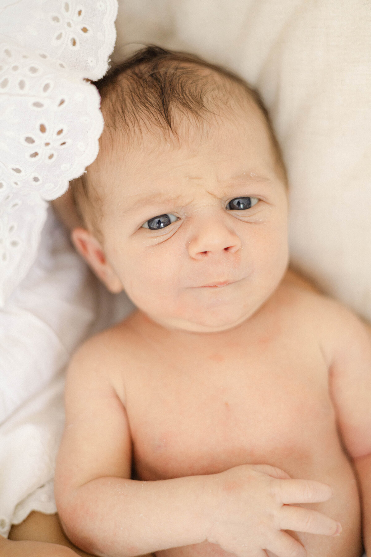 Newborn giving a serious look straight at the camera during lifestyle photos at home.
