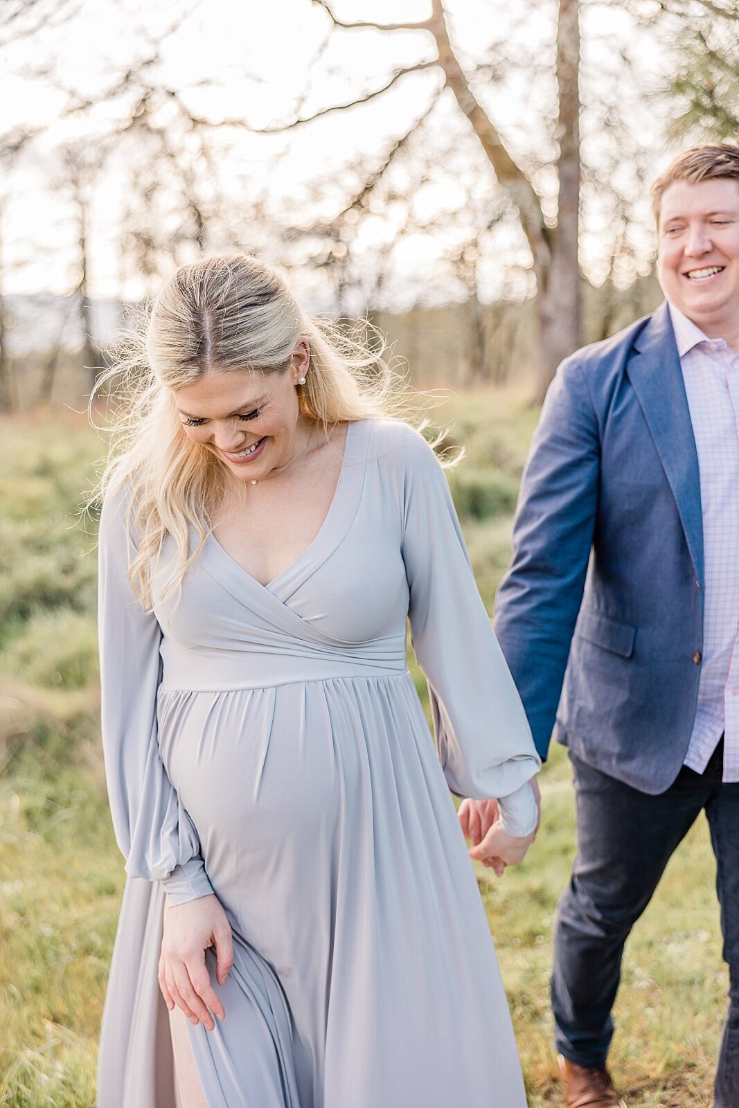 Pregnant mom laughing holding husband's hand in maternity photo session