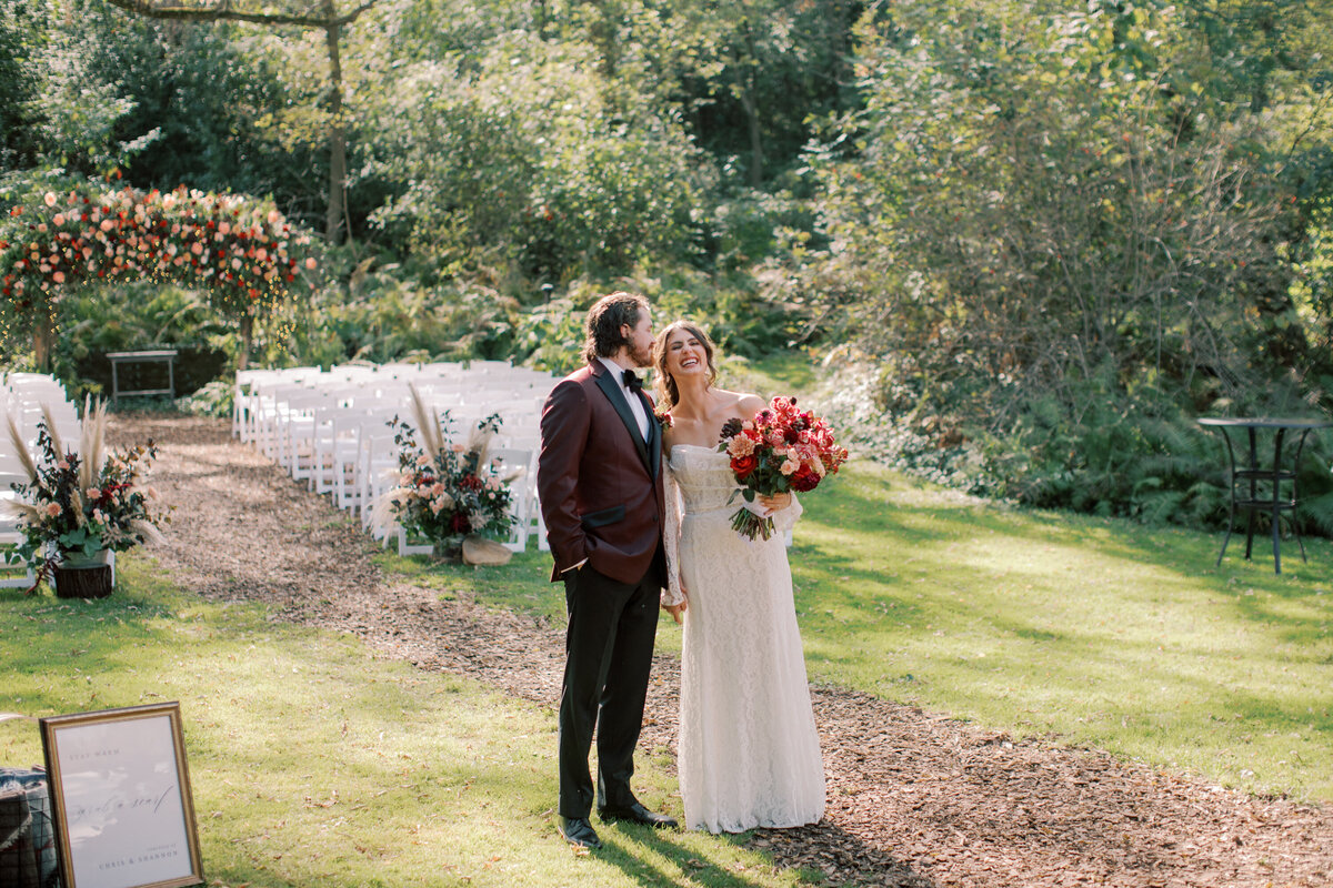 bride and groom at wedding venue. groom kissing his brides forehead 