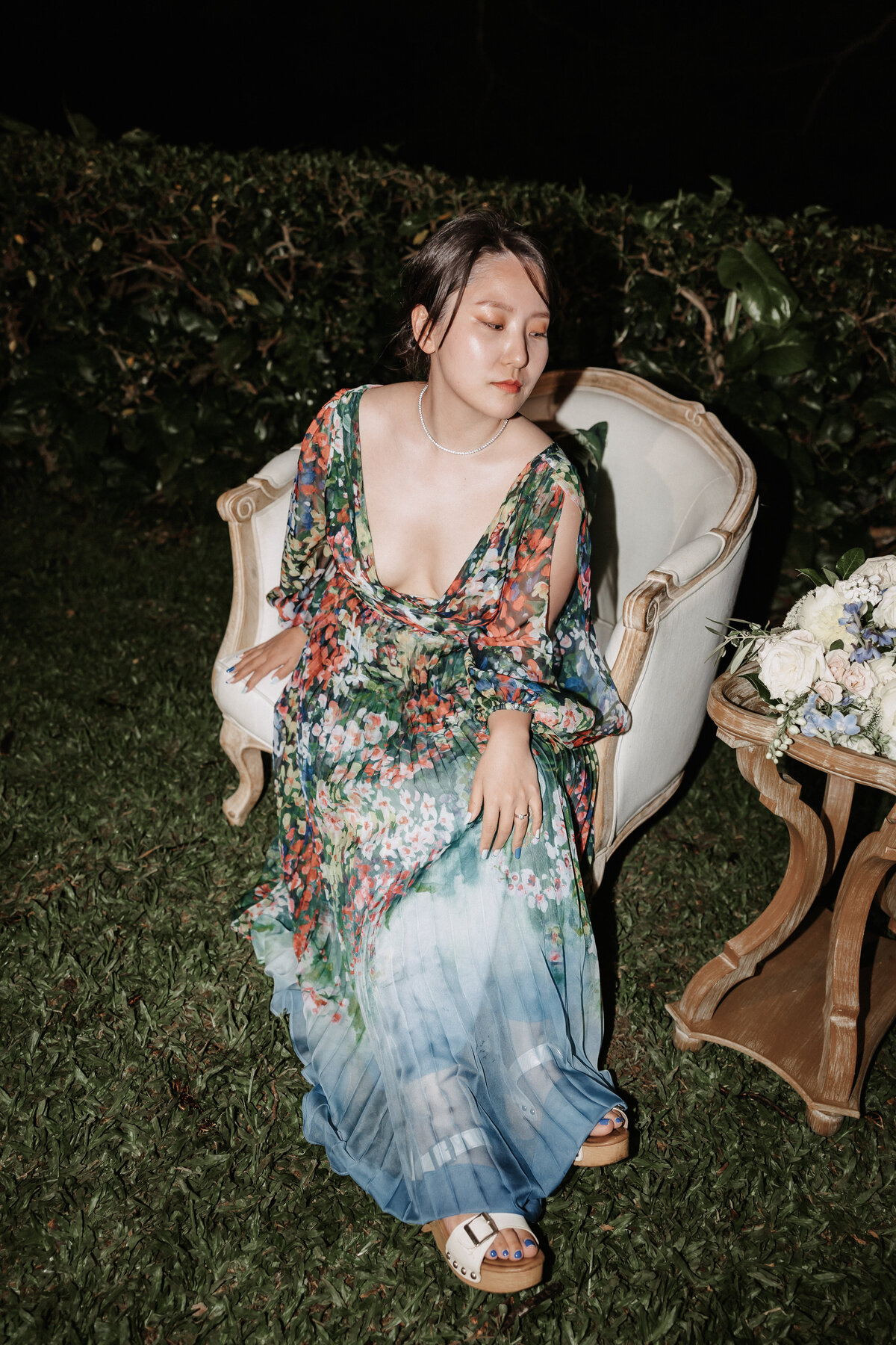 Asian girl in colorful dress poses while sitting on a lounge set