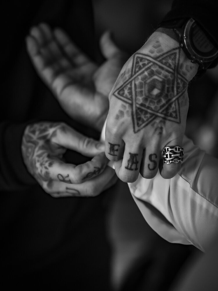groomsmen helping groom with shirt cufflinks