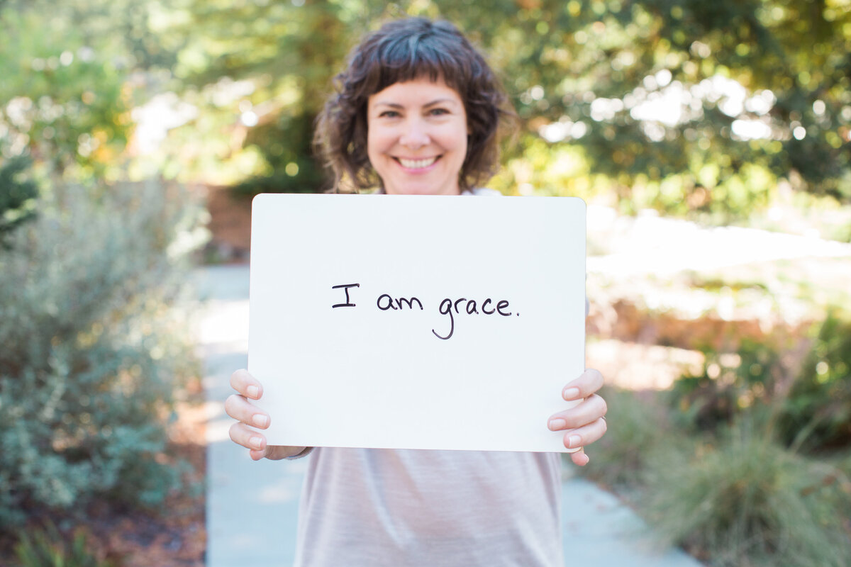 woman holding whiteboard sign that says I am grace
