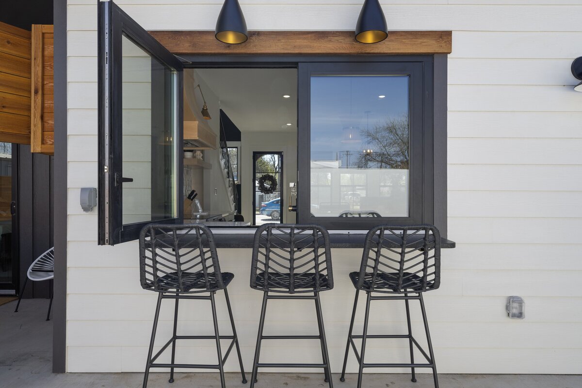 Charming outdoor barstool seating with window for indoor access at this two-bedroom, two-bathroom house with wine fridge, firepit, and two master suites located in the heart of the Silo District in Waco, TX.