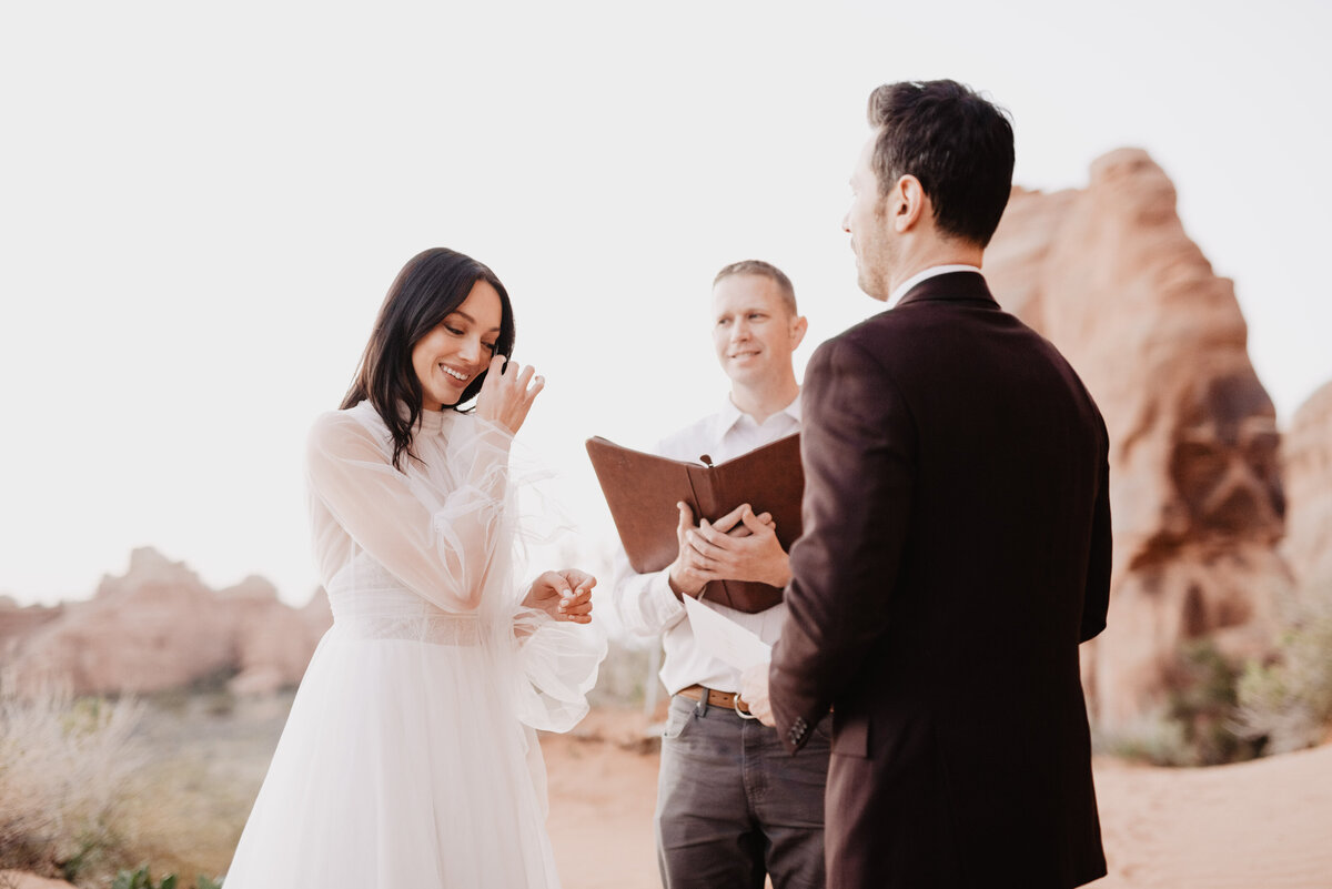 Utah elopement photographer captures bride wiping tears during intimate wedding ceremony