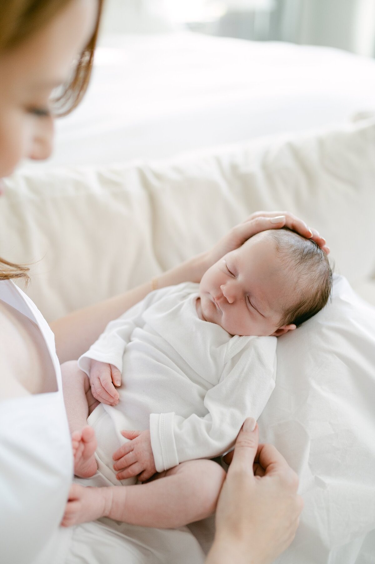 Close up photo of newborn baby from above, with mom's hands in the photos