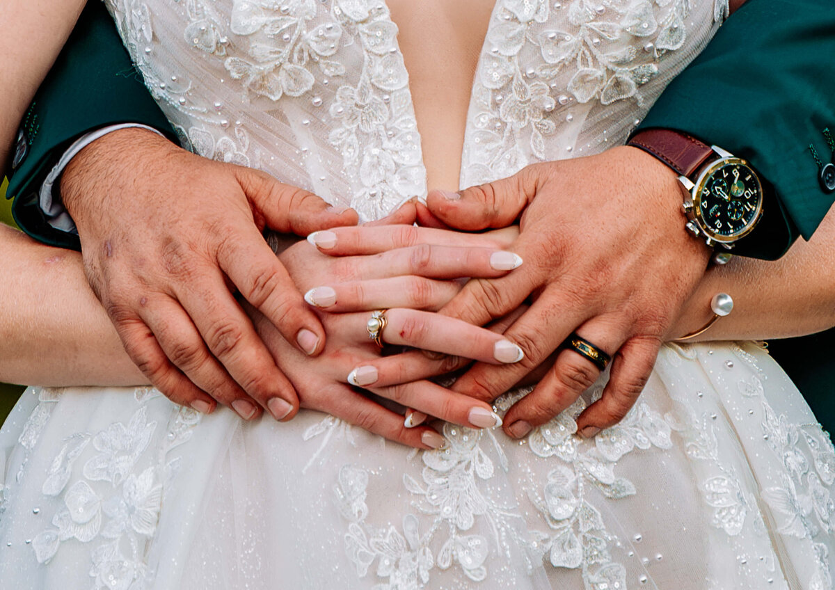 A close-up of a bride and groom's hands intertwined, symbolizing love and unity on their special day. - photo by Jamie Simmons