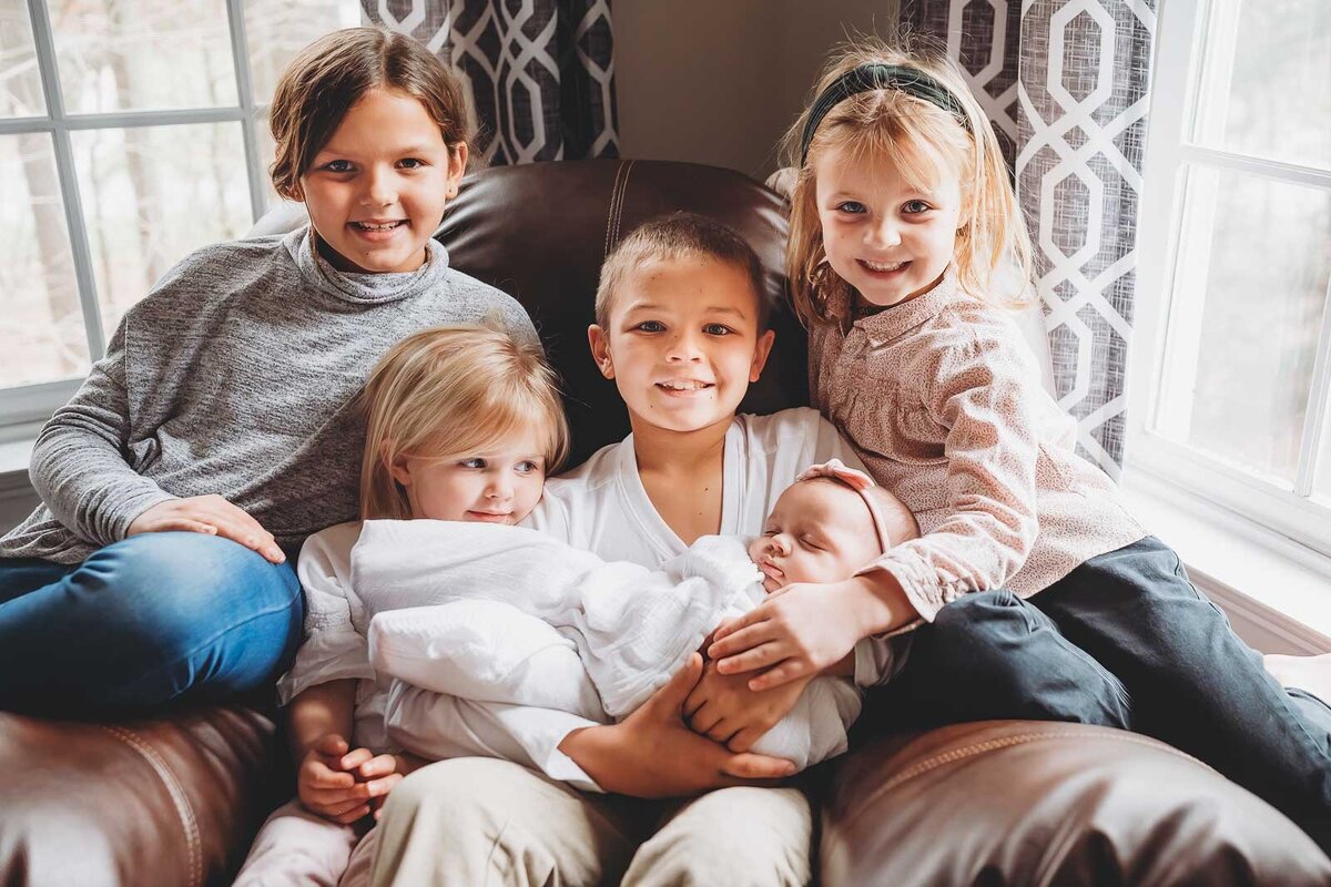 newborn-with-older-siblings-sitting-on-favorite-couch