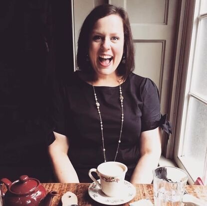 Amelia laughing over a cup of tea