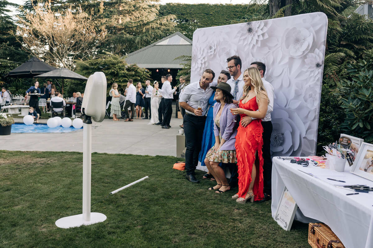 five wedding guests in a photo booth beside a pool on the lawn near ashburton in nz