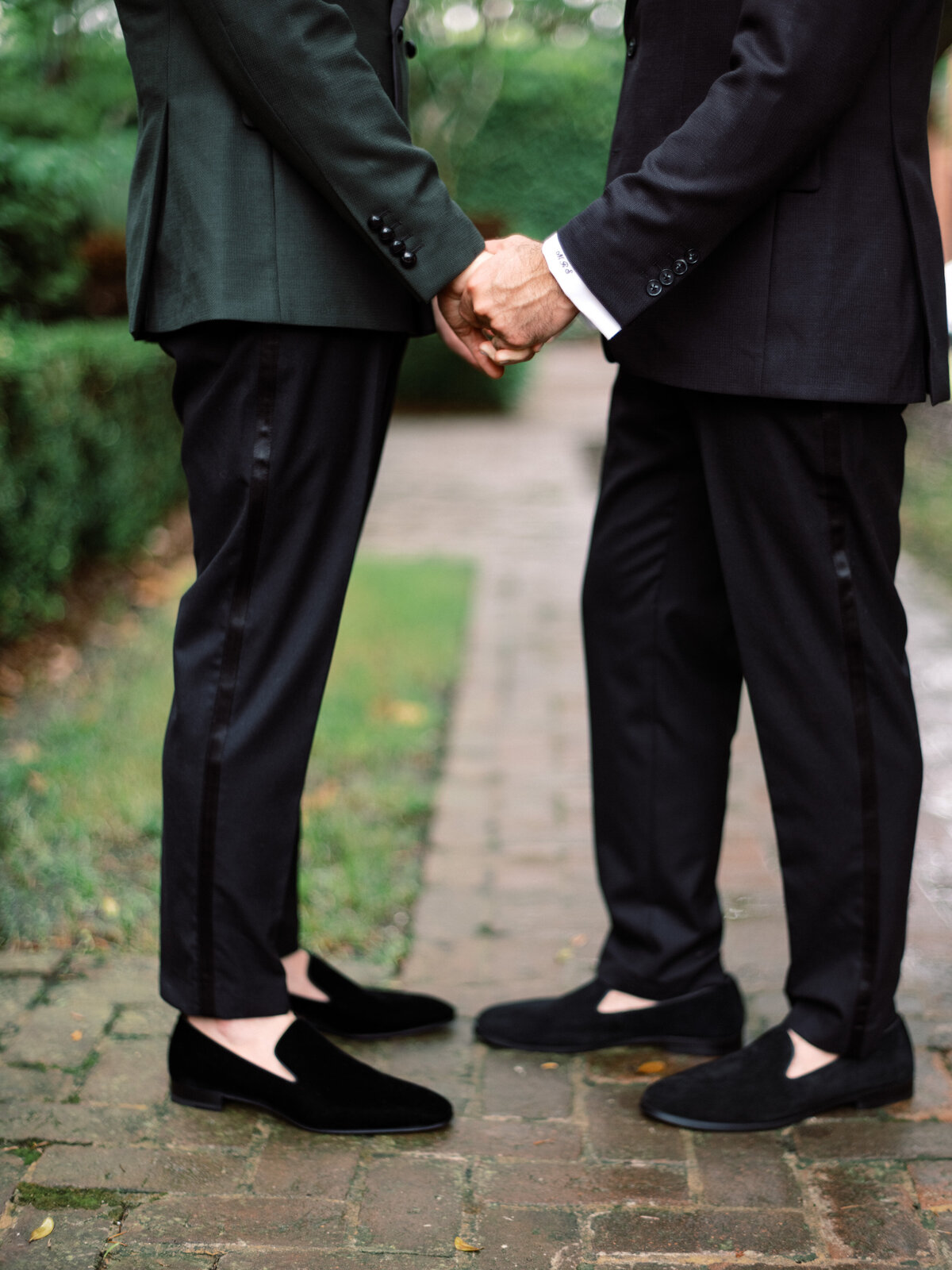 A romantic couple holds hands elegantly in their formal attire, showcasing style and affection against a lush garden backdrop, perfect for wedding themes and love stories.