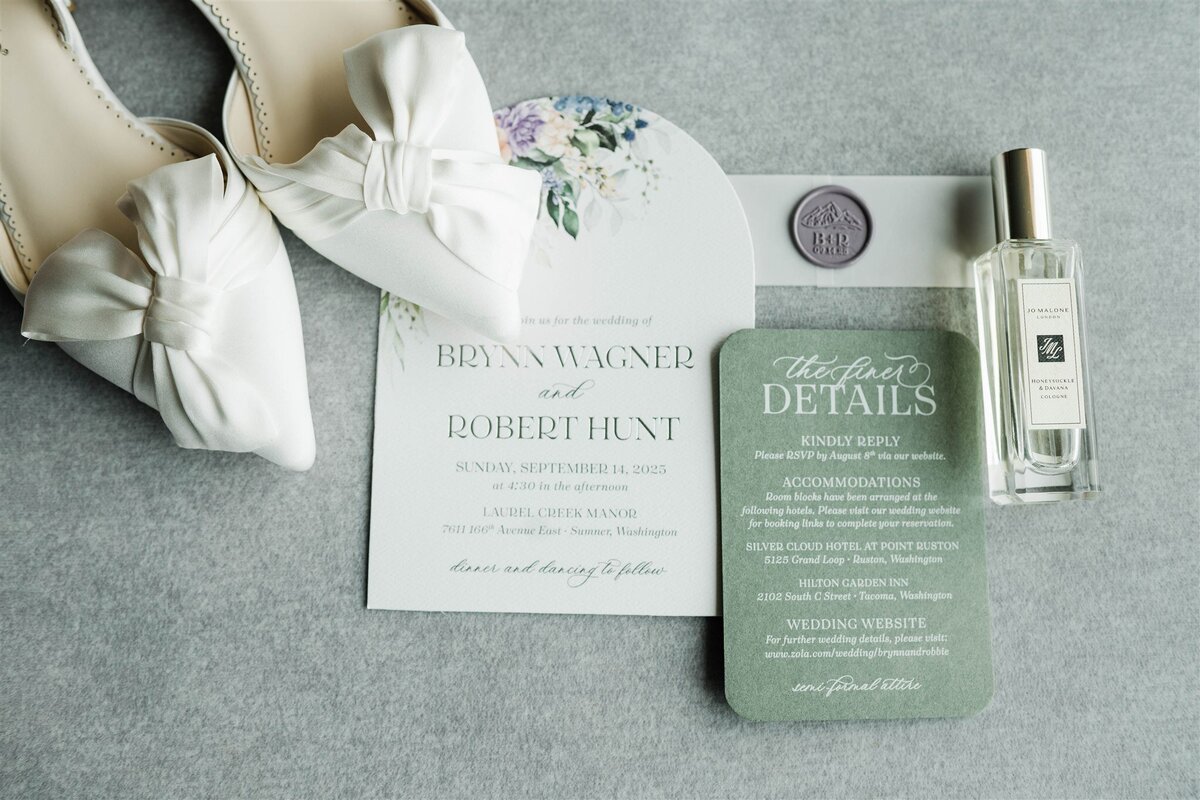 Flat lay of wedding invitations, florals, and rings styled on linen at Silver Cloud Hotel Ruston.