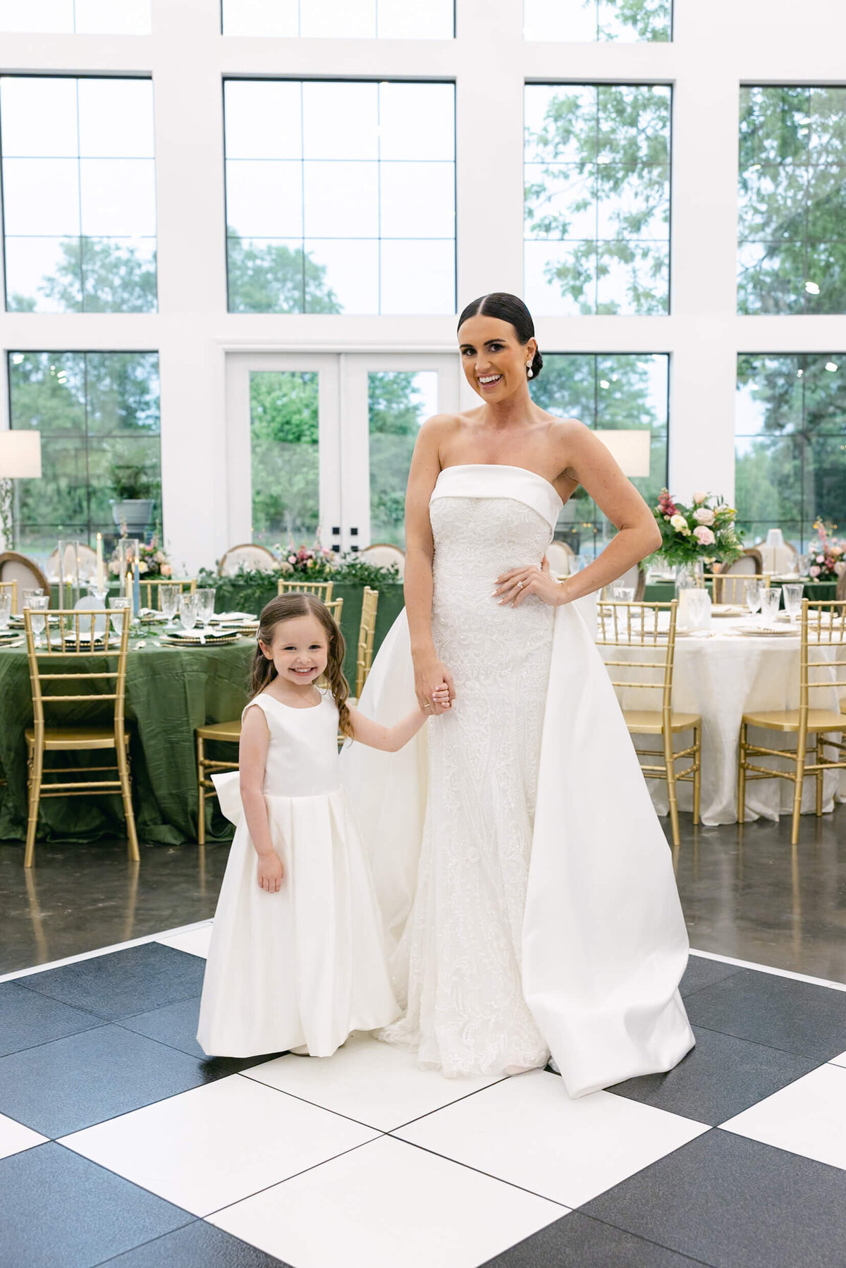 A wedding day photo of the bride in her white wedding dress with her ring barer who is also wearing a white dress