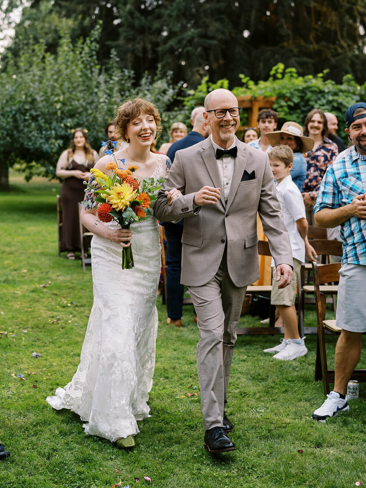 A bride and her father walking up the aisle and smiling. 