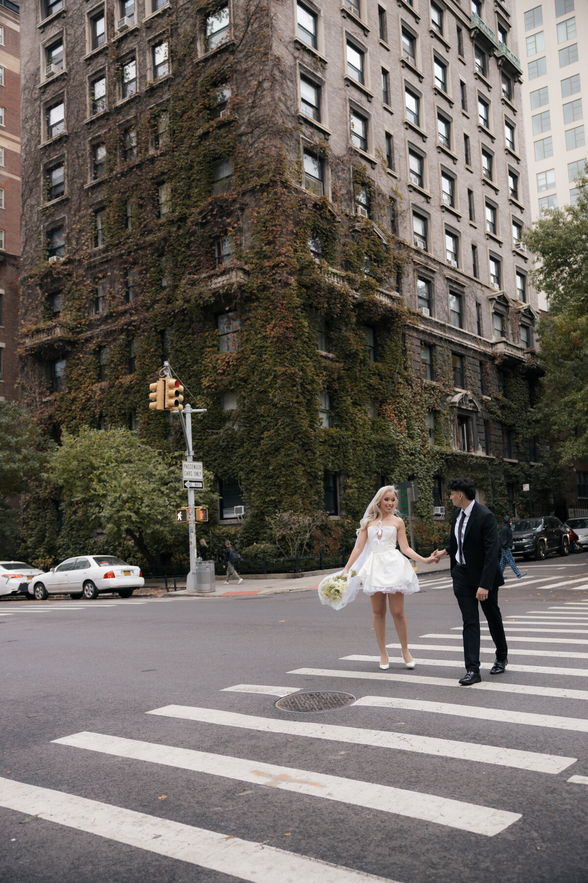 Candid moment of bride laughing as the groom twirls her on an NYC sidewalk.