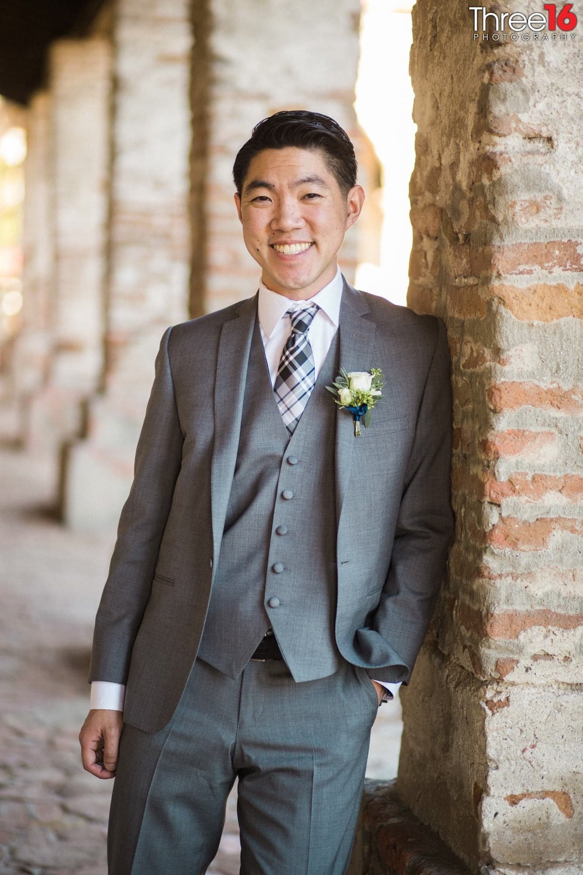 Big grin by the Groom as he leans against the brick pillar