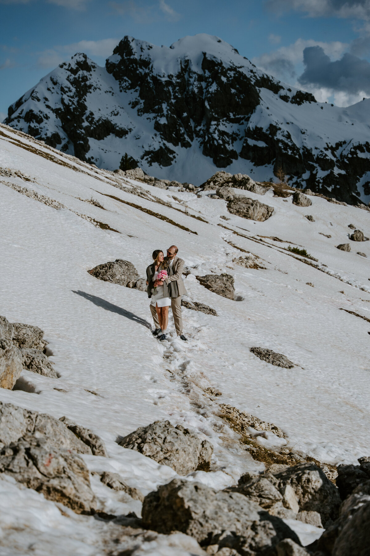 Couple walking rocky Dolomites trail with mountain views behind