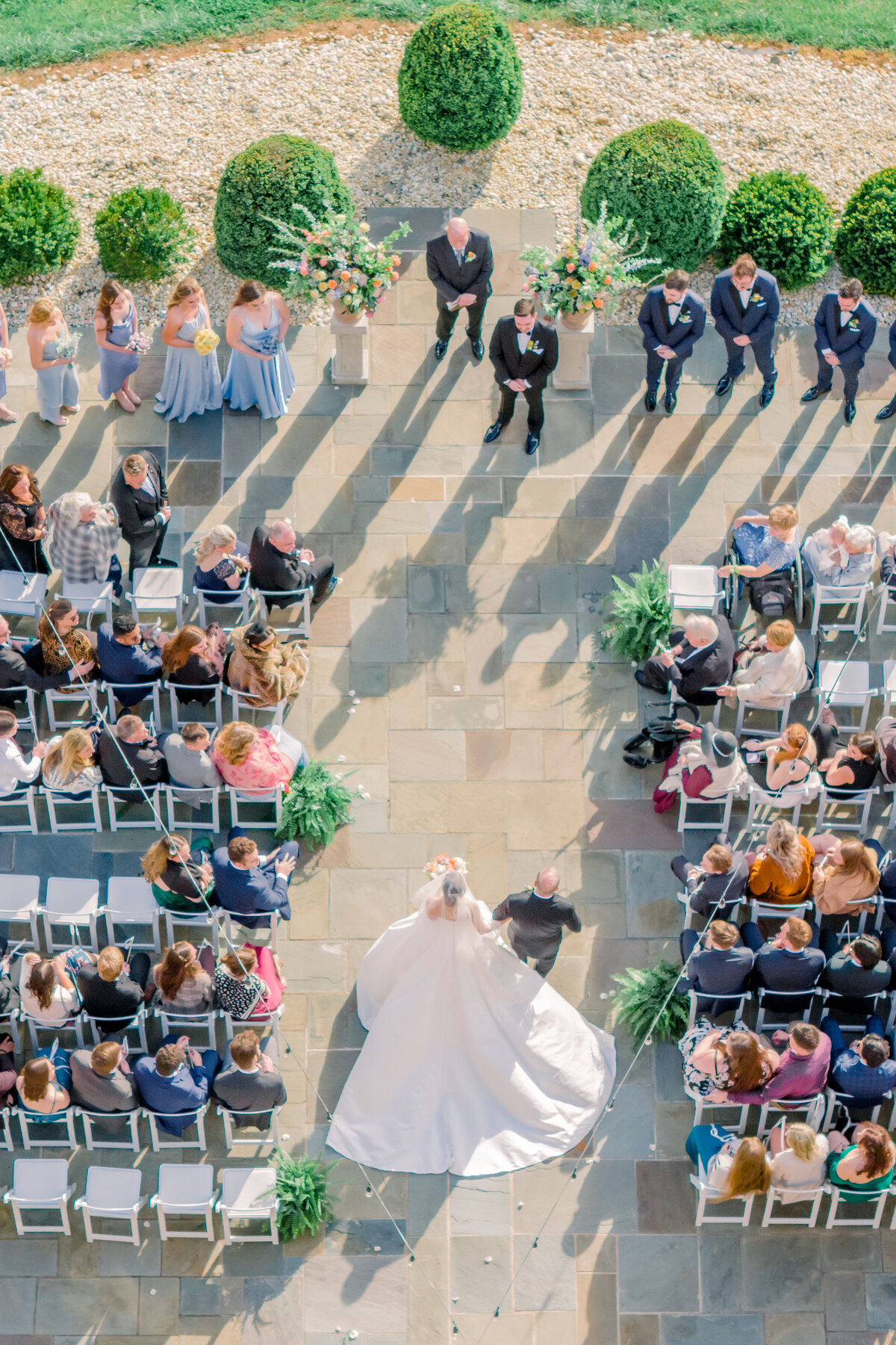 Drone image from above looking down on the father of the bride walking the bride down the aisle