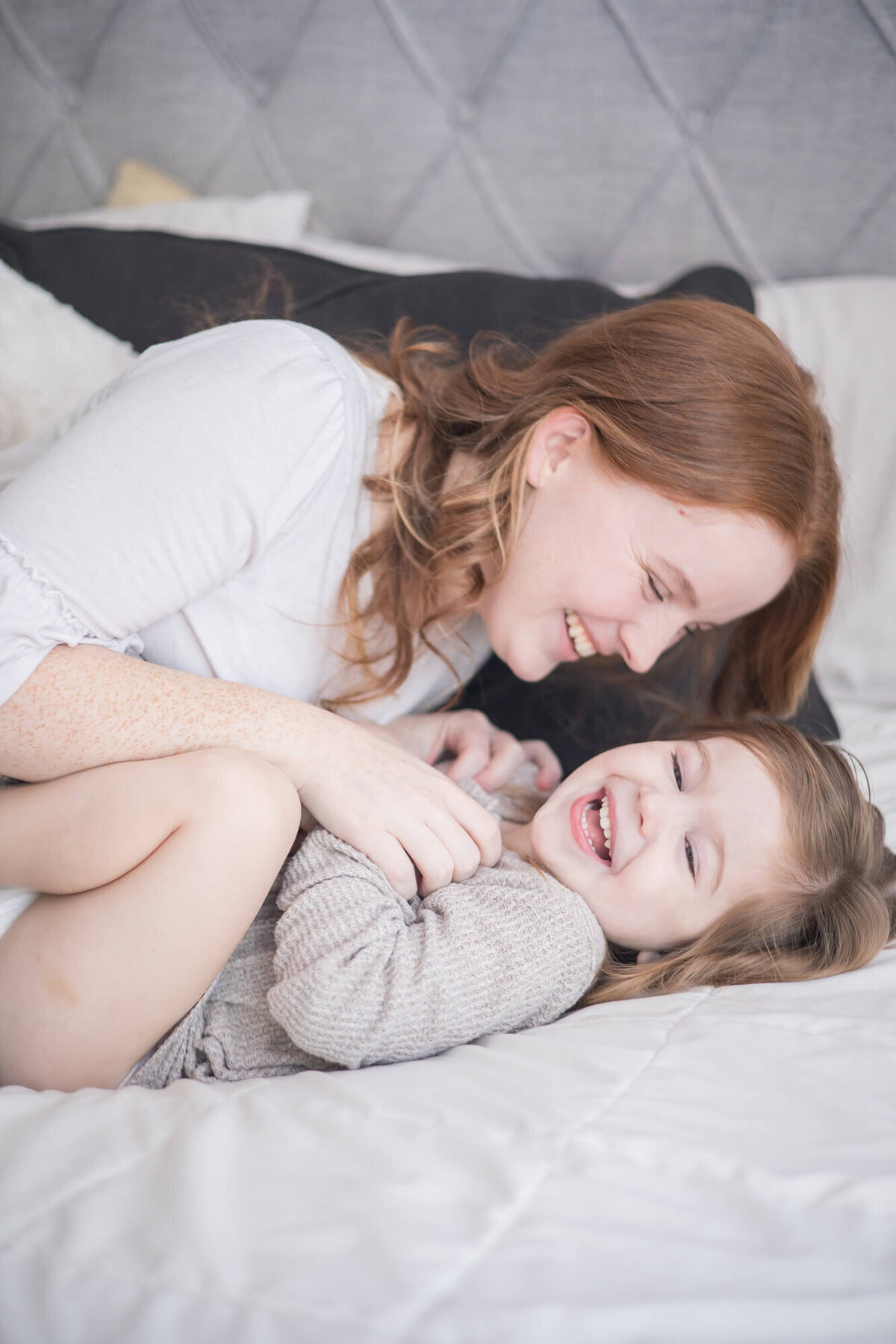 mom playfully tickling toddler daughter during a lifestyl in home newborn session