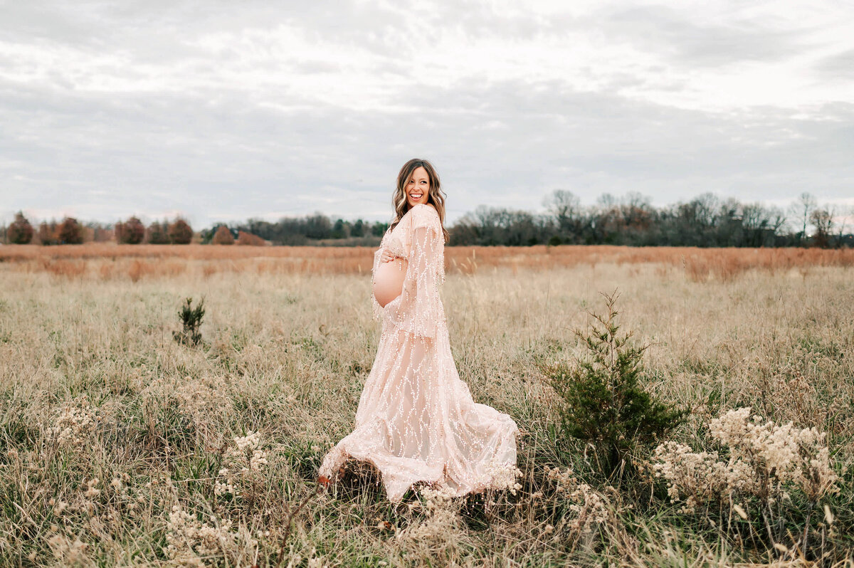 pregnant couple cuddling in field laughing in field captured by Branson MO maternity photographer