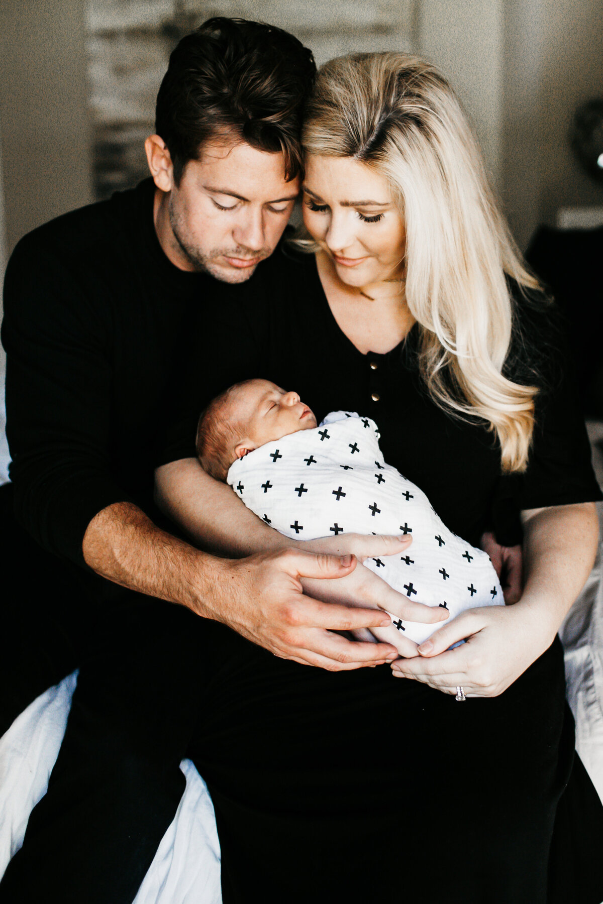 mom and dad holding newborn baby in home