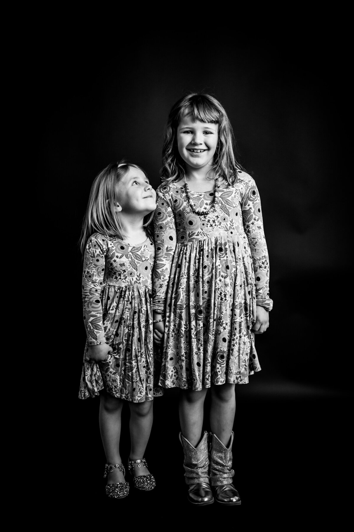 Striking portrait of sisters wearing flower dresses in black-and-white is captured during a children's session at the Pittsburgh photography studio