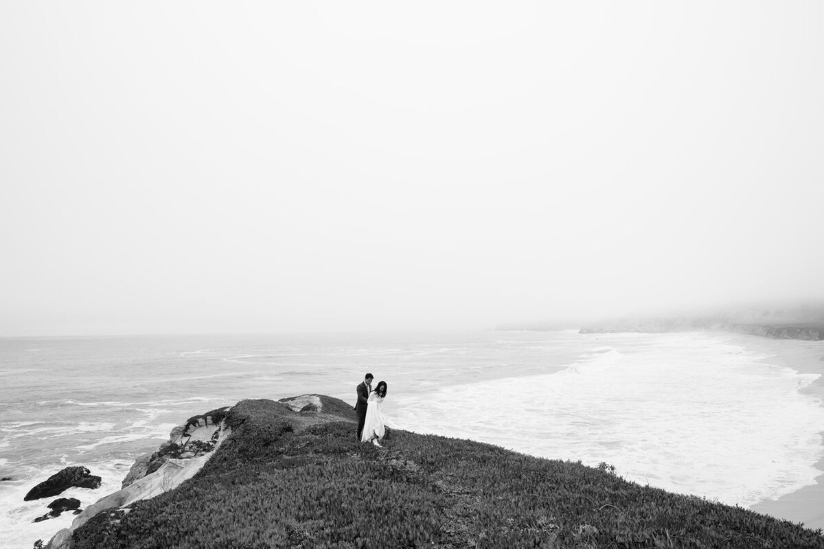 a couple by the edge of a cliff overlooking the ocean