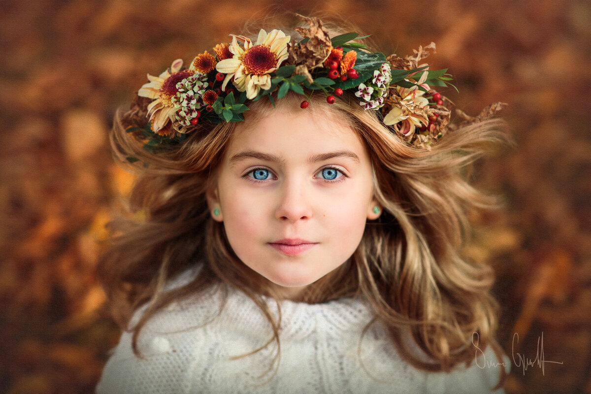 flicka i blomsterkrans bland höstlöv i vackra färger