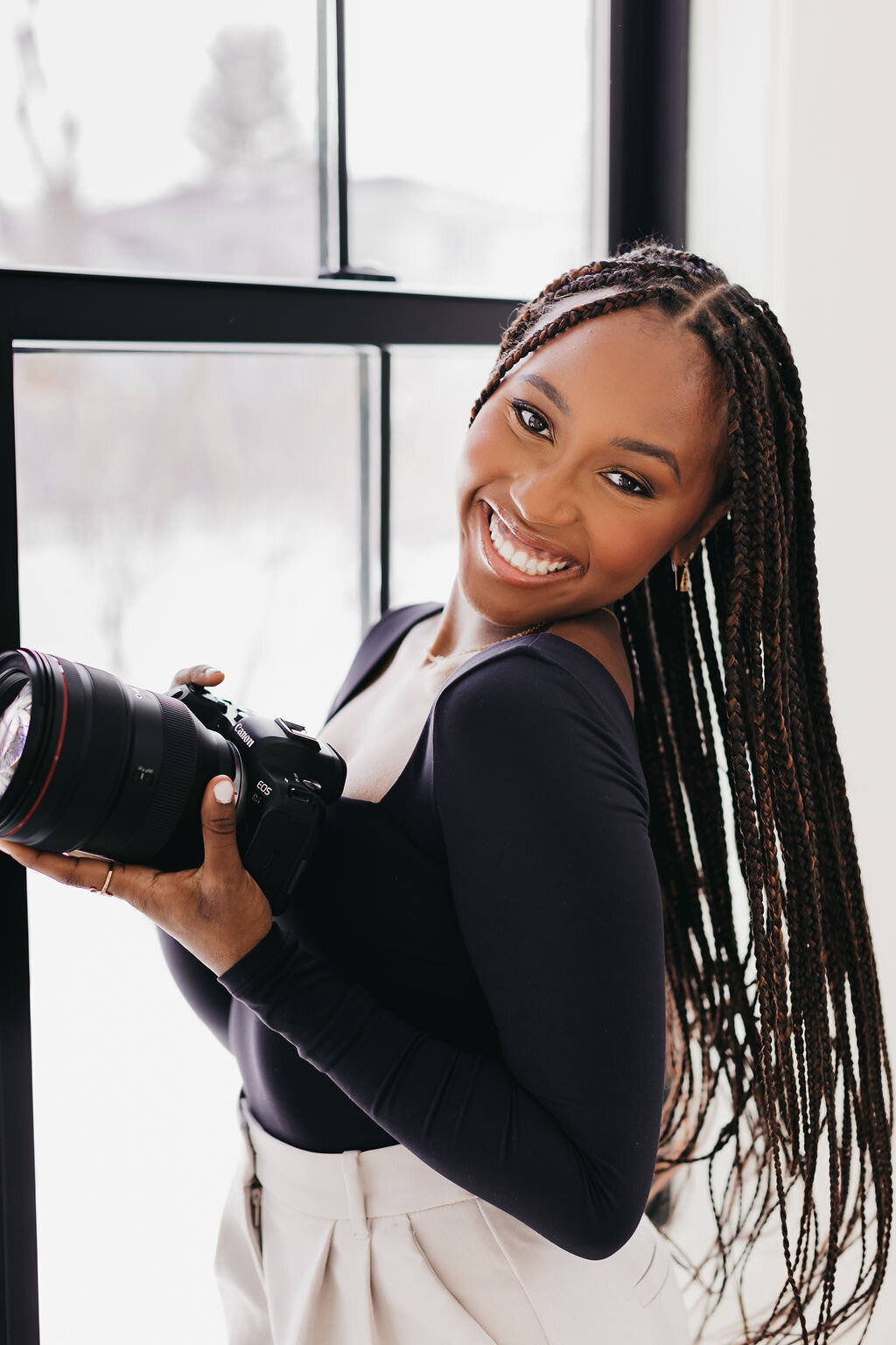 Juma Waganda in a black top smiling and holding her camera