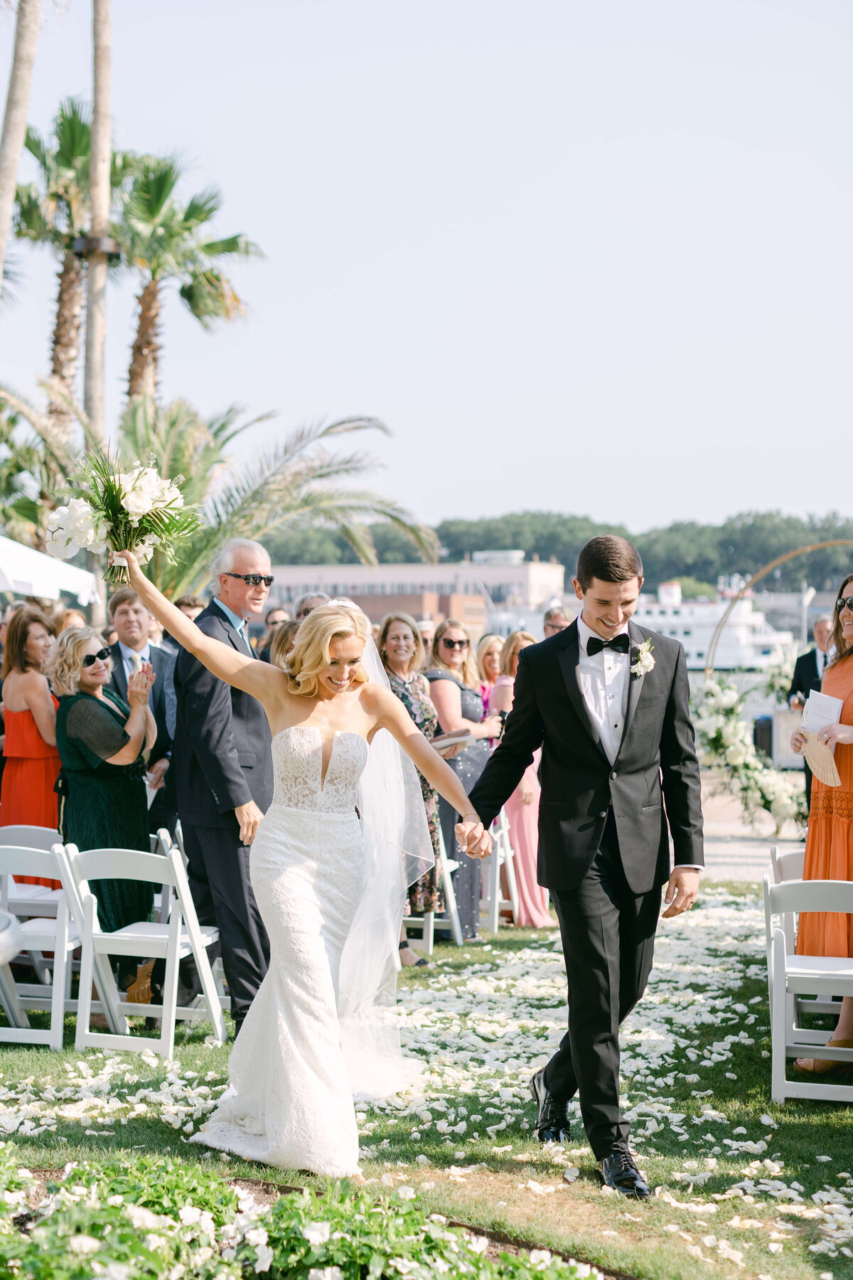 A bride holds up her bouquet after marrying her husband.