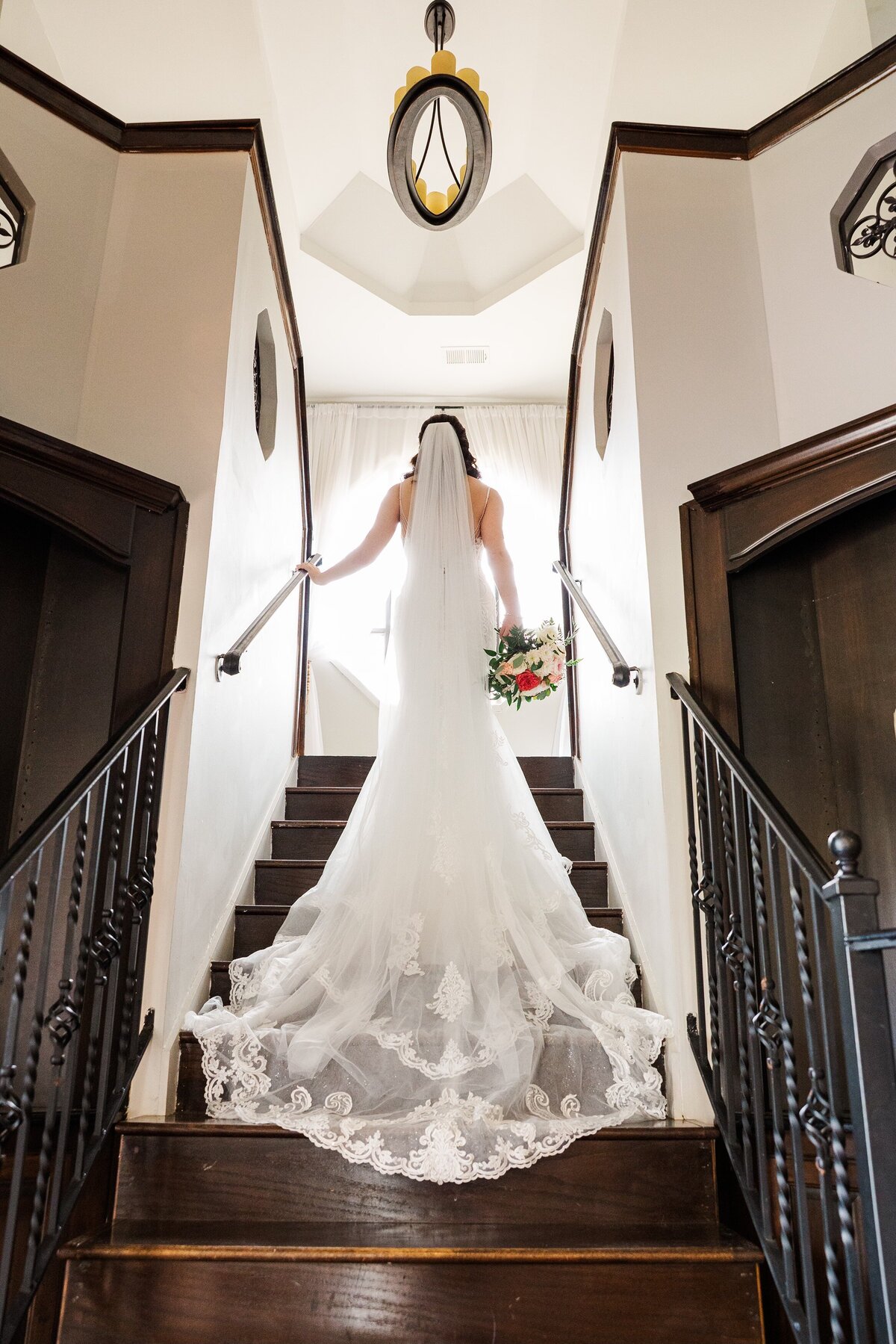 Bride shows the back of her dress as she walks up steps