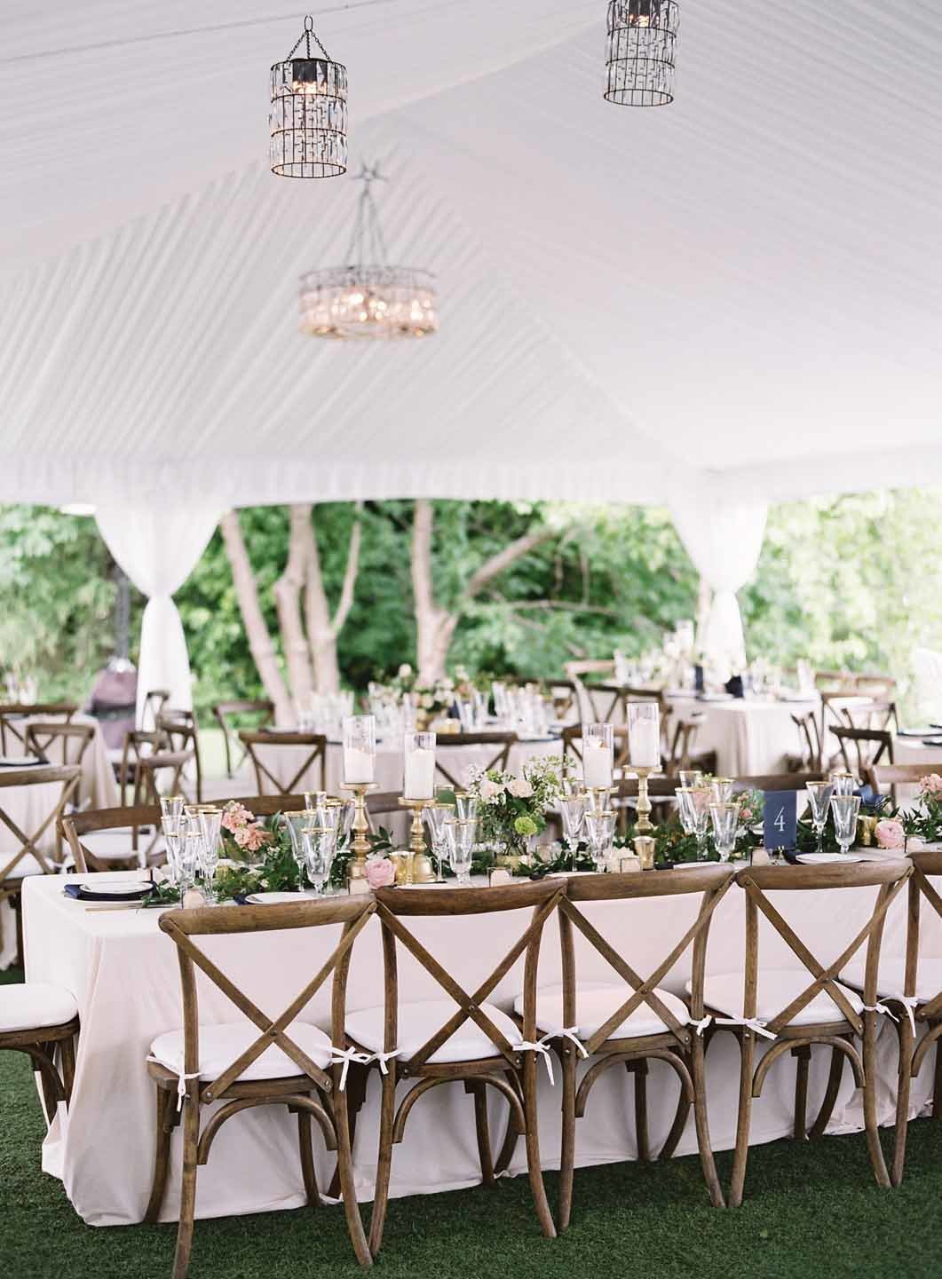 wedding reception in tent with crystal chandeliers, Vineyard chairs, long tables and floral centerpieces