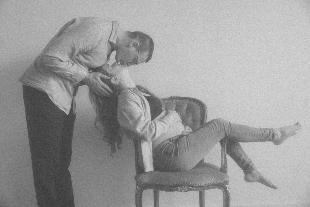 Couple kisses playfully as women holds her pregnant belly. 