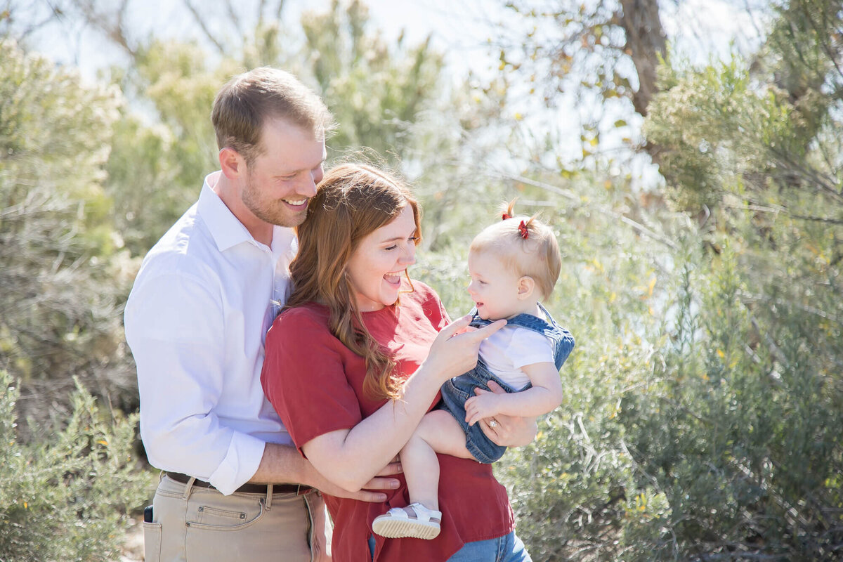 gorgeous redheaded couple playing with toddler girl during family portrait session