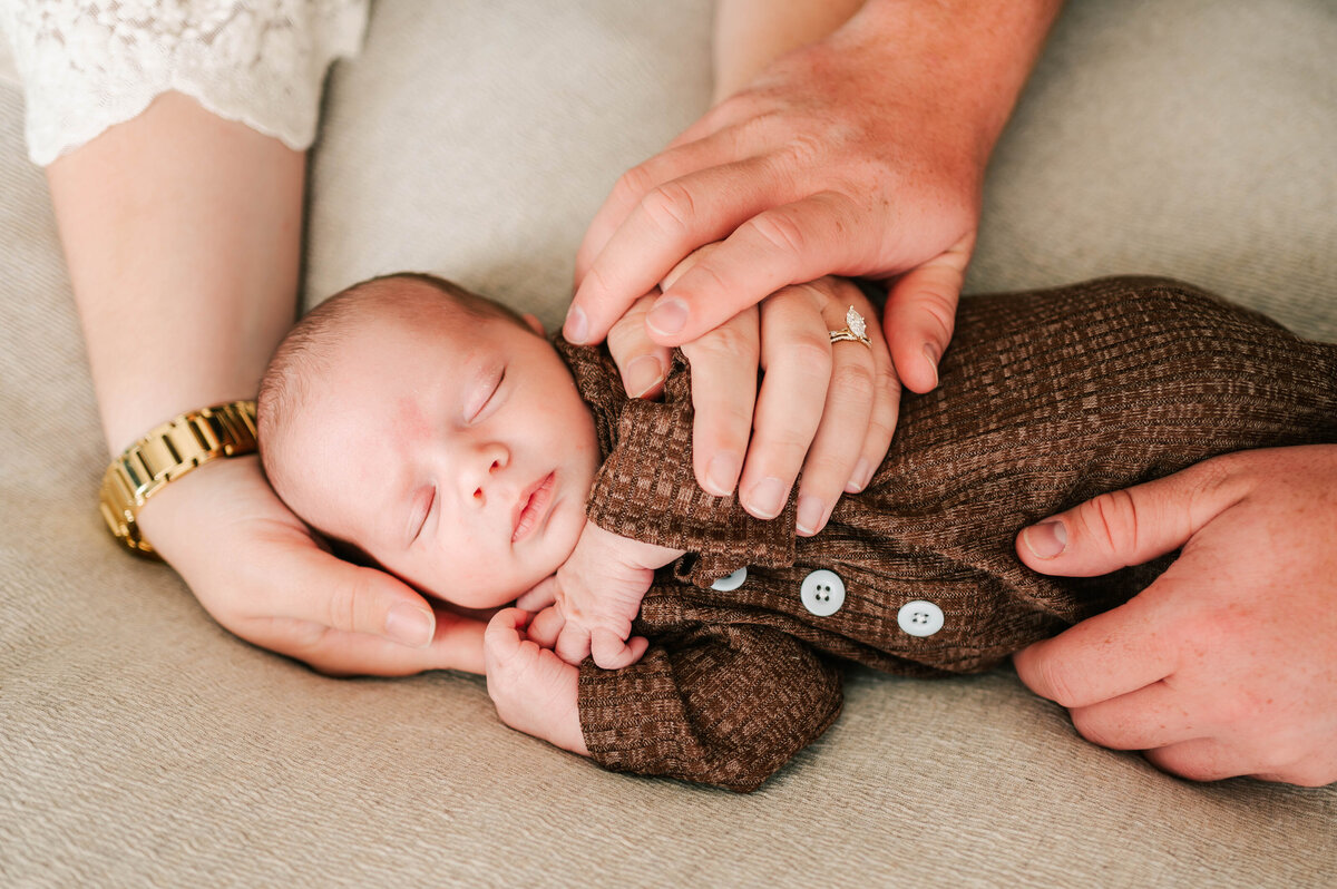sleeping baby boy in parents hands during Springfield MO newborn photography session