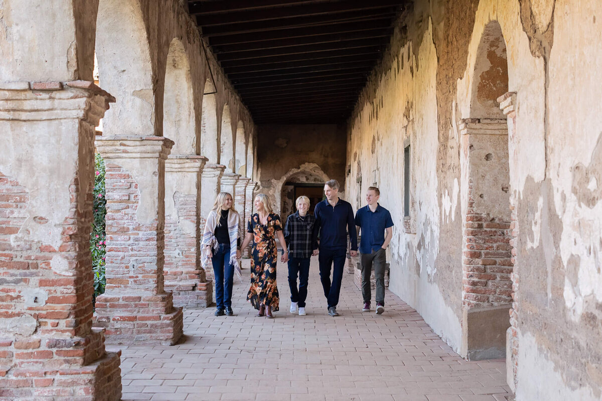 A family of five walking through a courtyard at the San Juan Capistrano Mission.