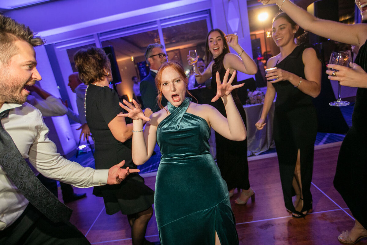 A woman in a green dress is dancing with a group of people.