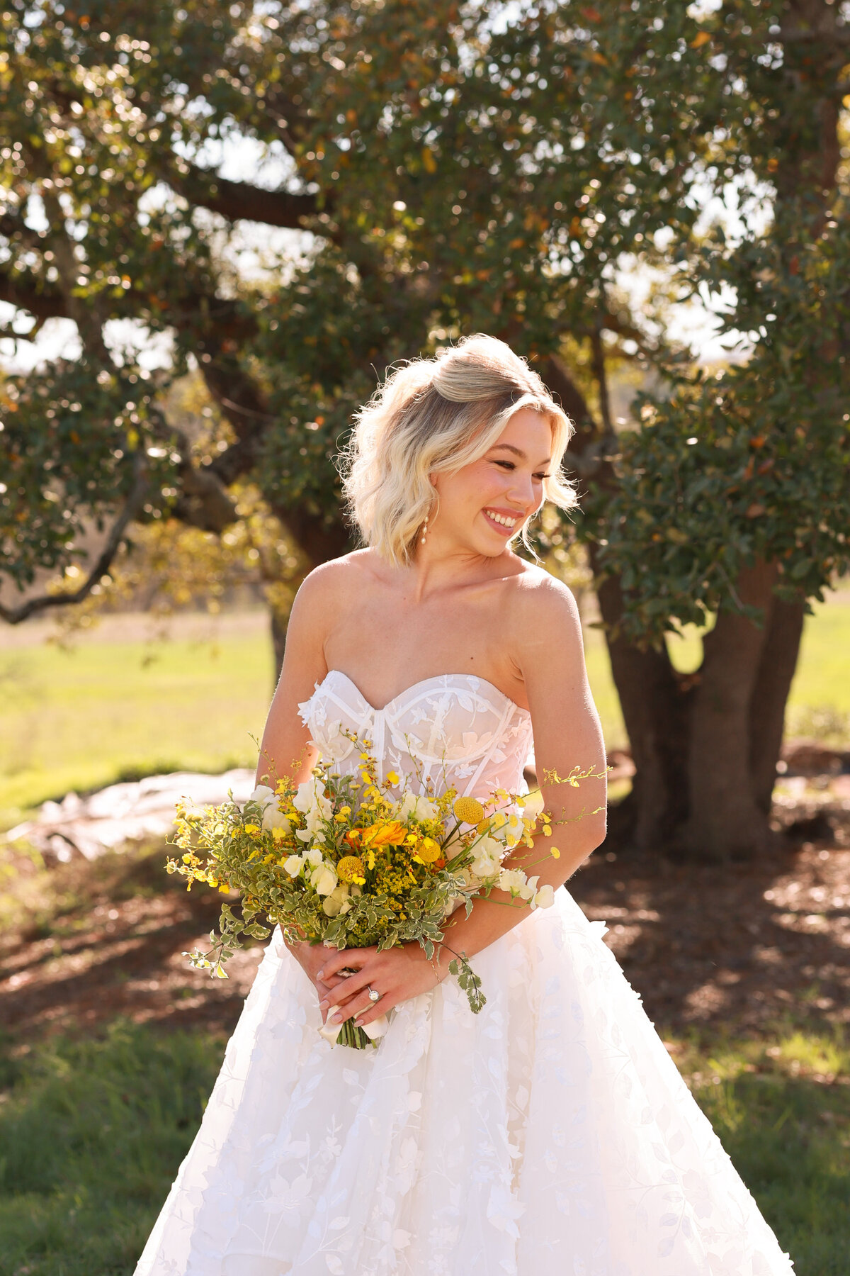 bride smiling over shoulder at Hewitt Oaks wedding venue in Austin Texas by Austin Texas Wedding photographer Amanda Richardson Photography