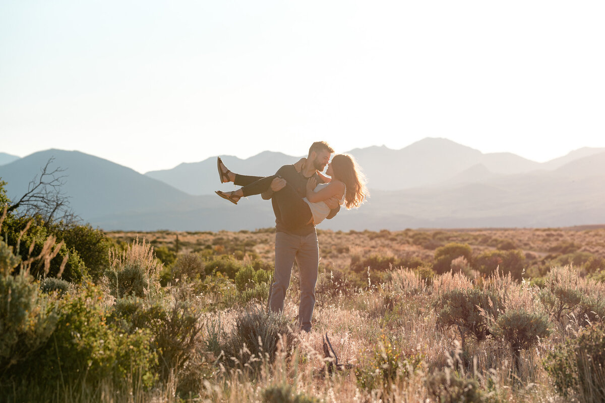 Man holding woman in cute couples photo set with mountains as the backdrop