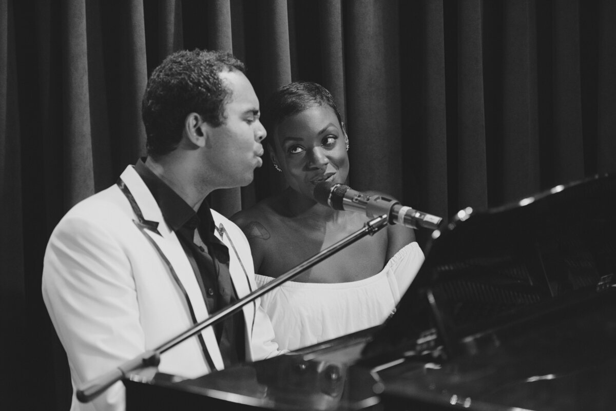 Two people sitting at a piano singing