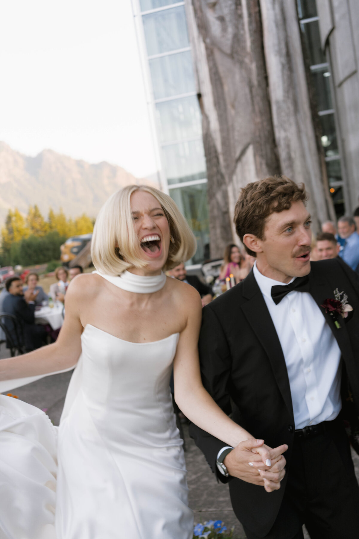 Bride laughing joyfully during wedding reception with groom in black tuxedo