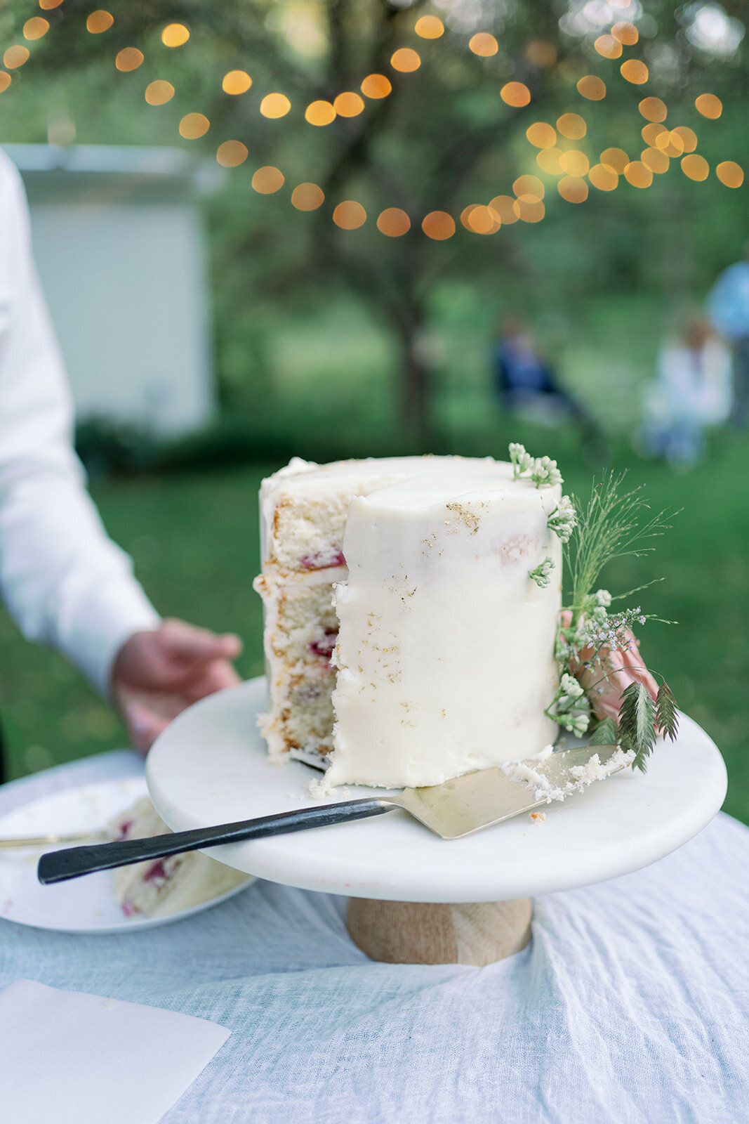 Minimalist white floral wedding cake photographed outdoors at Glasshouse Community during a summer Michigan wedding.