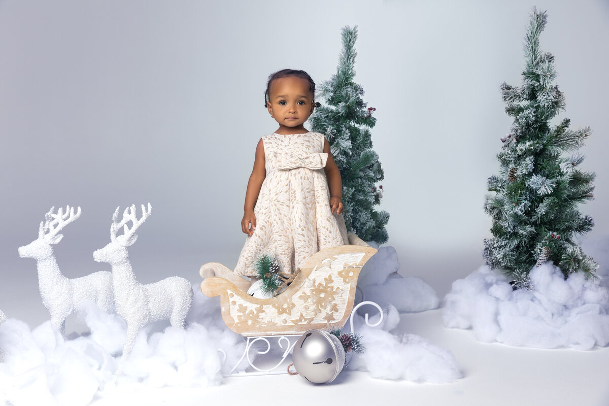 little girl standing with reindeers for a christmas mini shoot session in dmv