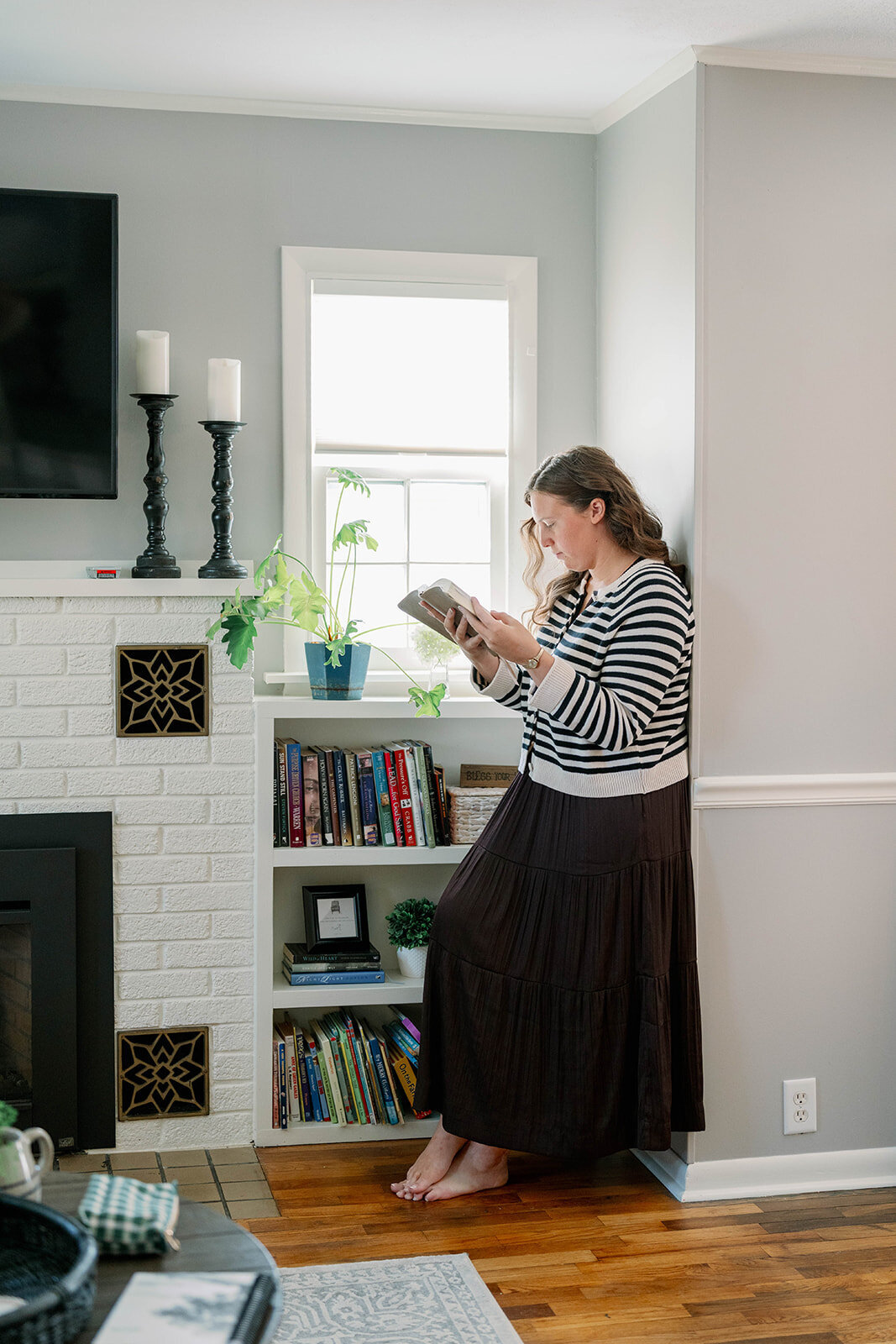 Woman reading a planner while sitting in a cozy living room near the fireplace during the Indiana branding session.