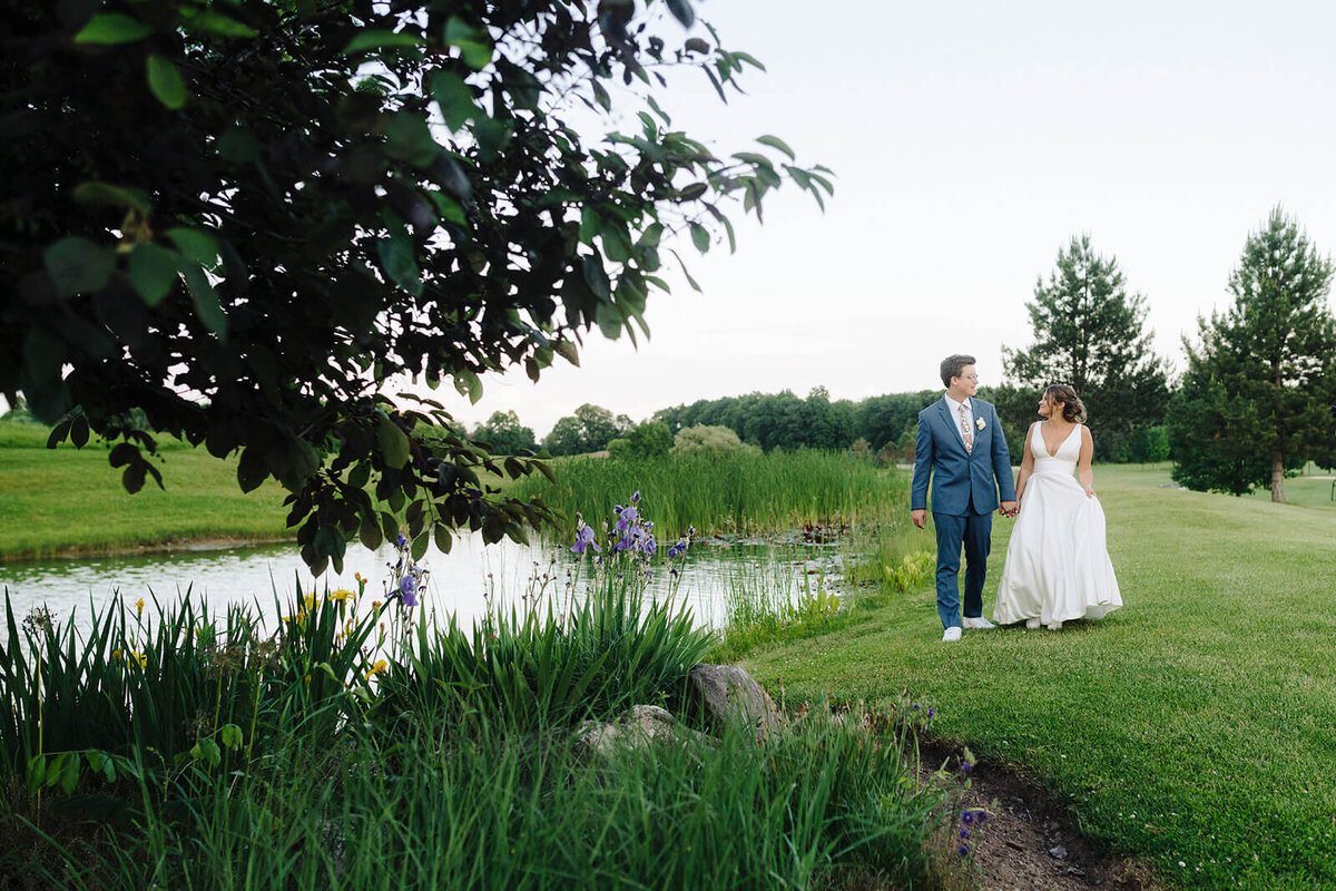 Bride and groom walking along river bank at Oswego, NY
