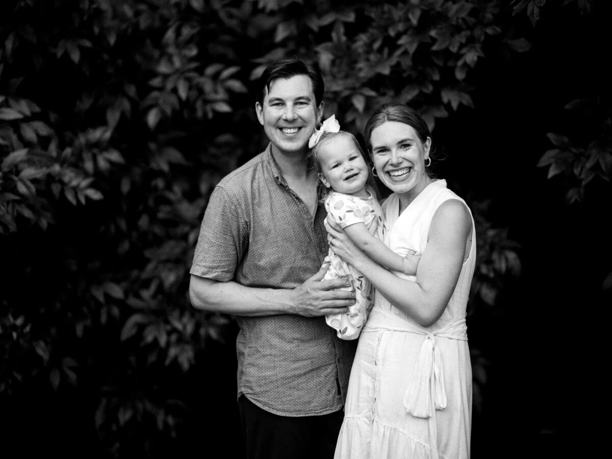 A small baby behind held in between her parents.