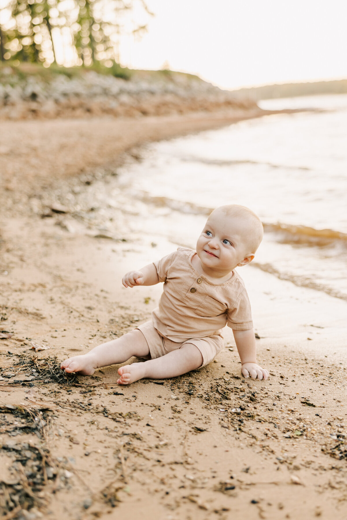 Baby boy sitting in the sand playing with the mud